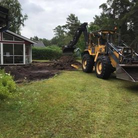 Traktor gräver upp gräsmatta.